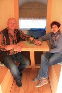 een man en vrouw aan een tafel in een hut bij Mini Hotel Übernachten Im Gurkenfass in Lübbenau