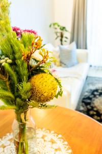 un jarrón lleno de flores sentado en una mesa en MARGARET FOREST RETREAT Apartment 129 - Located within Margaret Forest, in the heart of the town centre of Margaret River, spa apartment! en Margaret River