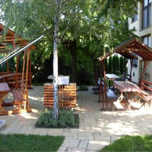 a patio with a tree and a table and chairs at Pegazus Vendégház in Hajdúszoboszló