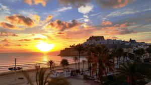 a sunset view of a beach with palm trees at La Cabaña in Peñíscola