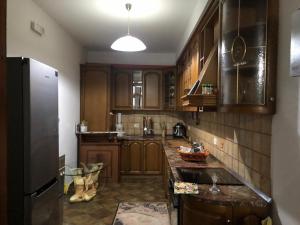 a kitchen with wooden cabinets and a black refrigerator at Kris's apartment in Lezhë