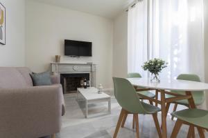 een witte woonkamer met een tafel en een bank bij LaLa Suites Corredera Centro in Jerez de la Frontera