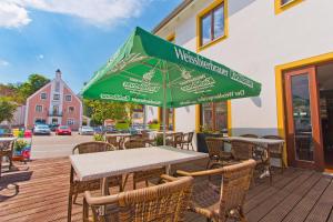 an outdoor restaurant with tables and chairs and umbrellas at Gasthof Postbräu in Siegenburg