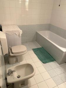 a bathroom with a toilet and a sink and a tub at Appartamento con giardino privato in La Salle