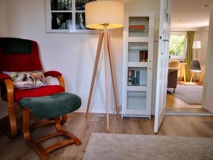 una camera con sedia rossa e lampada da pavimento di Ferienhaus Landhaus Am Hirtzborn a Marbach