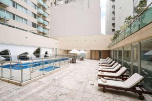 a building with a swimming pool and lounge chairs at Dazzler by Wyndham Buenos Aires Recoleta in Buenos Aires