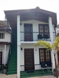 a white house with green stairs and windows at Jily Stay in Kandy