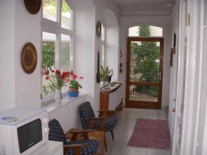 a living room with a tv and chairs and a door at Garden Szivárvány utcai Vendégház in Szeged