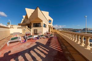 balkon z krzesłami i stołami na budynku w obiekcie MEDANO4YOU Carmen's Beach House w mieście El Médano