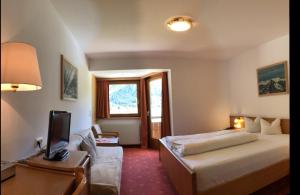 a hotel room with a bed and a desk with a television at Piz-Hotel in Sankt Leonhard im Pitztal