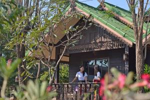 dos personas de pie en un balcón de una casa en Thai Thai Sukhothai Resort, en Sukhothai