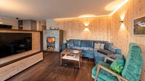 a living room with a blue couch and a tv at Silent Luxury Chalet LAIET in San Valentino alla Muta