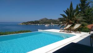 una piscina con sillas y vistas al océano en Apartments Villa Mirjana, en Mlini
