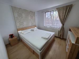 a small bedroom with a bed and a window at Morii Lake Apartment in Bucharest