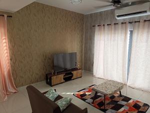 sala de estar con TV de pantalla plana en la pared en Mulberi Homestay 4BR 3Bth(8-10 px), en Port Dickson