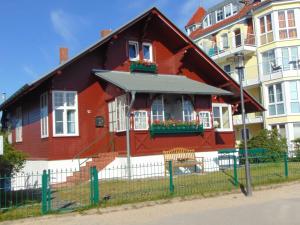 ein rotes Haus mit Blumen vor einem Gebäude in der Unterkunft Strandvilla Whg 01 in Bansin