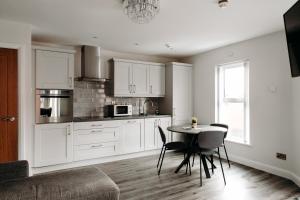 - une cuisine avec des placards blancs, une table et des chaises dans l'établissement Mountain View Apartments, à Newcastle