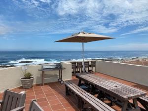 a patio with an umbrella and a table and benches at Nothing But View in Hermanus