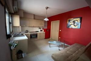een keuken met een bank en een rode muur bij Prosilio Apartment in Thessaloniki