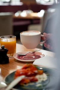 a person holding a cup of coffee and a plate of food at Townhouse Dresden in Dresden