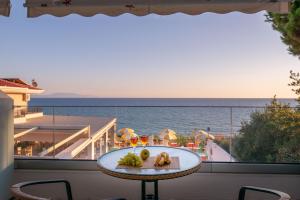a table on a balcony with a view of the ocean at Hotel Dimitra in Ligia