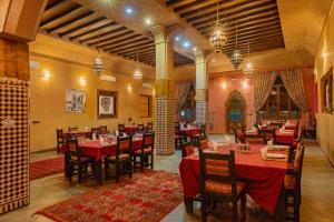 a restaurant with red tables and chairs in a room at Kasbah Hotel Ziz Palace Rissani in Rissani