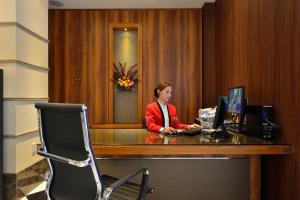 a woman sitting at a desk with a computer at Kariyushi LCH. Izumizaki Kencho Mae in Naha