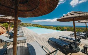 a resort with a pool and chairs and umbrellas at Résidence Les Terrasses de Rondinara in Bonifacio