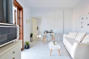 Roberto's Apartments في رودا: غرفة معيشة بيضاء مع أريكة بيضاء وطاولة