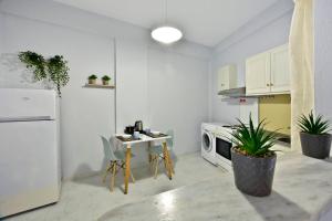 Roberto's Apartments في رودا: مطبخ وثلاجة بيضاء وطاولة بالنباتات
