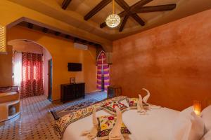 um quarto com uma cama e uma televisão num quarto em Kasbah Hotel Ziz Palace Rissani em Rissani