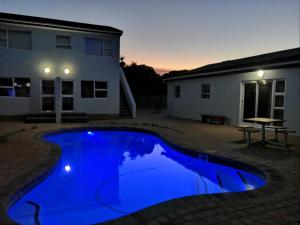 a blue swimming pool in front of a house at Southeaster in Bloubergstrand
