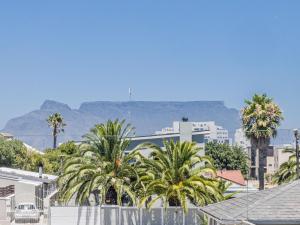 a city with palm trees and mountains in the background at Southeaster in Bloubergstrand +6 photos