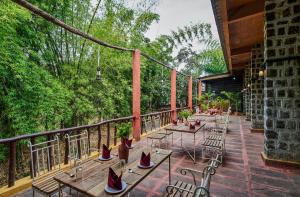 eine Terrasse mit Tischen und Stühlen auf dem Balkon in der Unterkunft WelcomHeritage Jungle Home Pench in Khawāsa