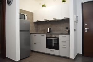 a kitchen with white cabinets and a refrigerator at Ginevra Home in Sesto San Giovanni