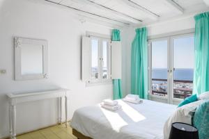 a bedroom with a bed and a window with the ocean at Xydakis Apartments in Mýkonos City