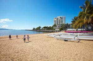a group of people walking on a beach with boats at Mariners North Holiday Apartments in Townsville