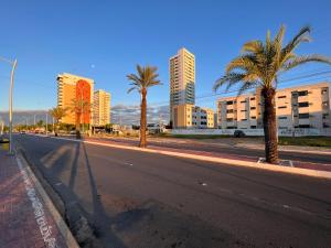an empty city street with palm trees and buildings at Vale Hospedar Orla Apart in Petrolina