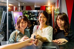 three women sitting at a counter looking at their cell phones at Kashiba Hotel Flower Style (Adult Only) in Kashiba