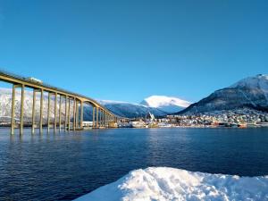 a bridge over a body of water with snowy mountains at Tromso Coco Apartments in Center in Tromsø