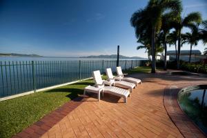a row of white chairs sitting next to a body of water at Mariners North Holiday Apartments in Townsville