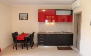 cocina con mesa, sillas y armarios rojos en Apartments Logos, en Cavtat