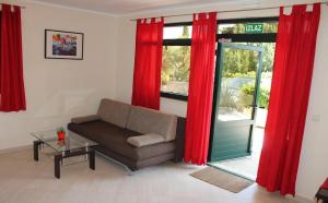 a living room with a couch and red curtains at Apartments Logos in Cavtat
