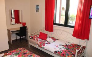 a bedroom with a bed and a desk and red curtains at Apartments Logos in Cavtat