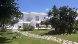 a white house with palm trees in the yard at Villa Katy Salento in Campomarino