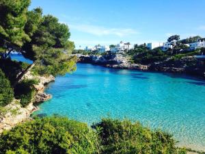 ein Fluss mit blauem Wasser, Bäumen und Gebäuden in der Unterkunft Cala Ferrera HOME&ME in Felanitx