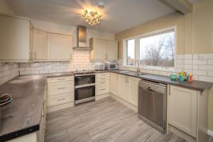 a large kitchen with white cabinets and a window at Granville Heights: 3-bed family home in Eastbourne