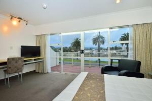 a room with a bed and a desk and a large window at Senator Motor Inn in Gisborne