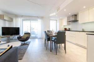 a kitchen and living room with a table and chairs at SERRENDY Apartment with swimming pool in Cannes