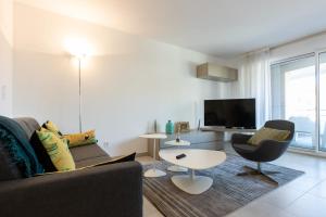 a living room with a couch and a table and a tv at SERRENDY Apartment with swimming pool in Cannes